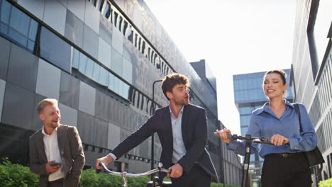 joyful coworkers going street with eco scooter bicycle. happy business people