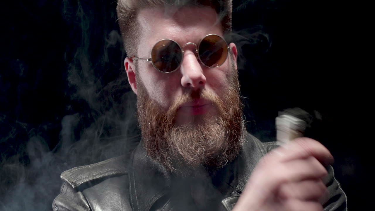 Man vaping with round glasses and leather jacket