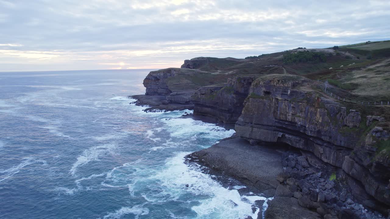 Drone capture the aerial height of blue sea hitting the shore of the island of Isla, Cantabria