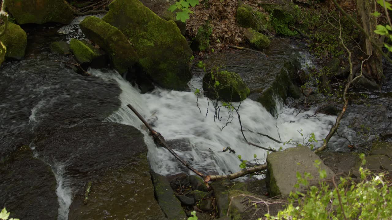 wide shot looking down at Lumsdale waterfalls with rocks and vegetation in foreground at Lumsdale, Matlock