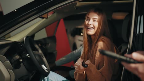 concesionario de automóviles dando llave al dueño del coche nuevo. satisfecha feliz cliente mujer caucásica cliente mujer sentada al volante de un coche nuevo haciendo una prueba de conducción antes de comprar auto mientras el asistente de tienda masculino ayuda
