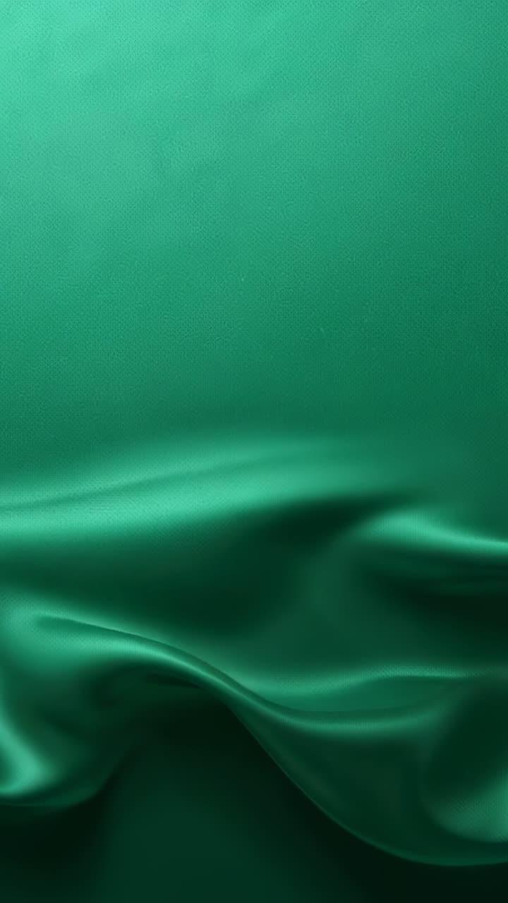 Vertical video: Shifting hidden hanger causing green satin drape making waves in studio highlights
