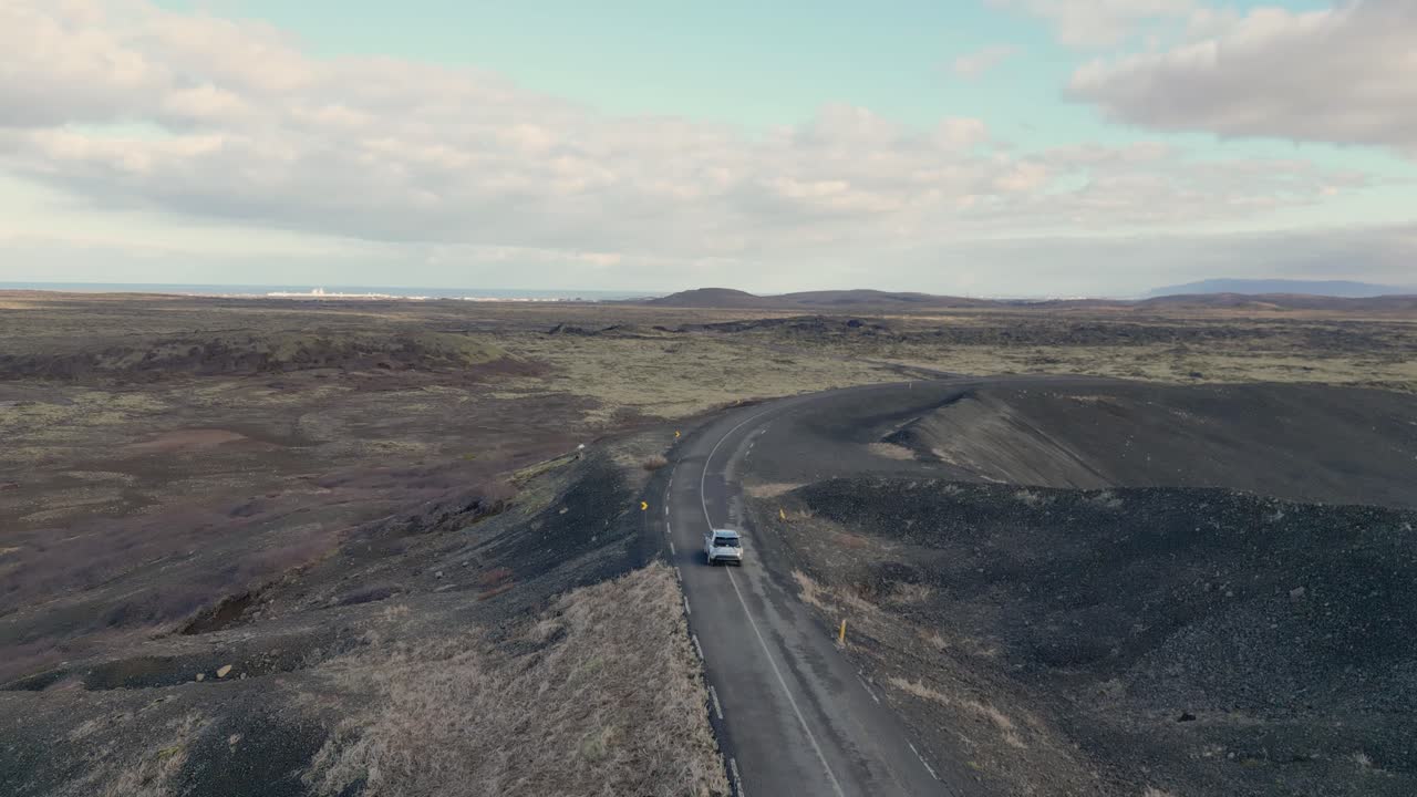 el coche conduce a través de una carretera interminable en el desierto islandés, rodeado de roca volcánica y musgo suave
