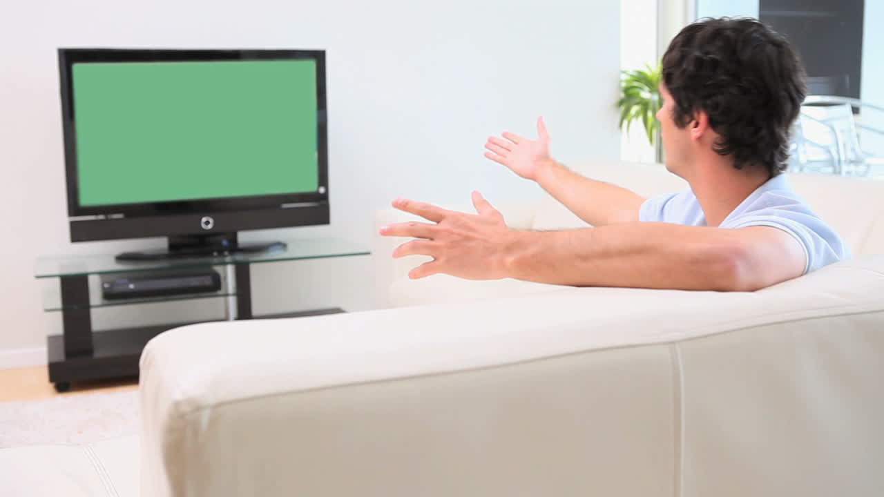 남자 는 말 하는 동안 텔레비전 을 보고 있다