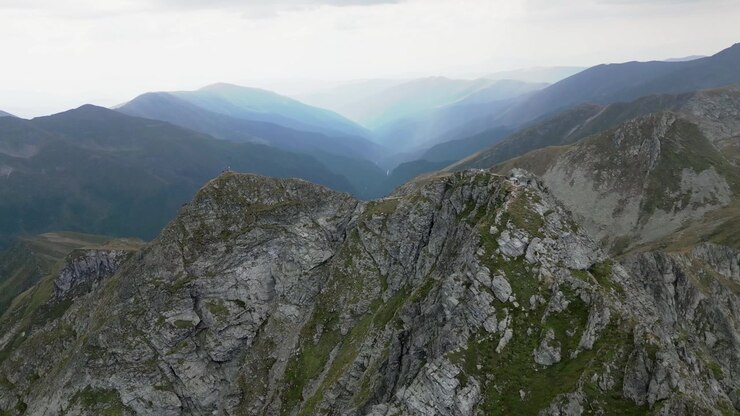 Drohnenflug um einen Berggipfel mit wunderschönen Bergen und Landschaft im Hintergrund, Karpaten, Rumänien, Europa, Sommer.