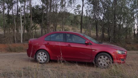 un coche mitsubishi lancer rojo desgastado abandonado en una tierra rural en australia - tiro completo