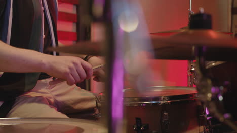 unrecognizable man playing drums in recording studio