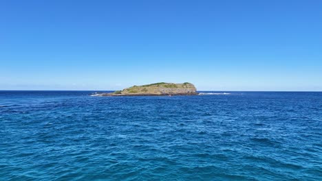 isla rodeada de océano bajo un cielo azul claro