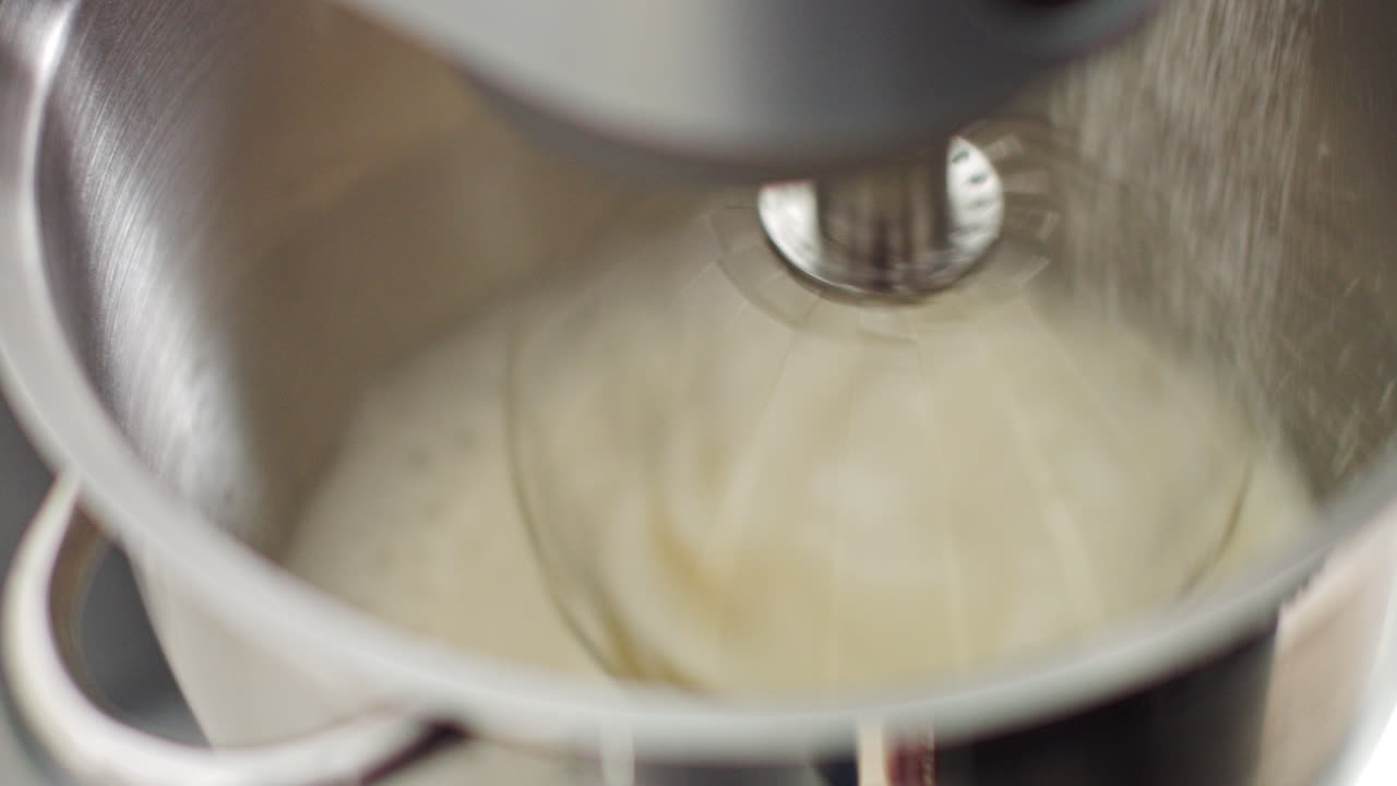 Whipping egg whites with sugar in food processor chef adding sugar to the bowl of modern silver