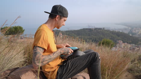 drone pilot men looking at aerial footage with laptop on top of mountain