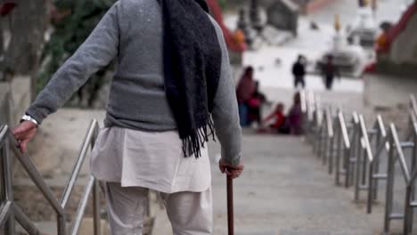vista trasera de un anciano con un bastón bajando las escaleras en la pagoda de swayambhunath en katmandú, nepal.