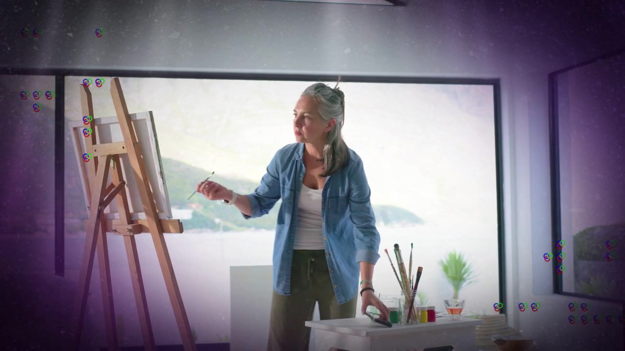 Mulher artista em estúdio com vista para o mar, pintando tela, usando pincéis, pegando o telefone, filmando o progresso.
