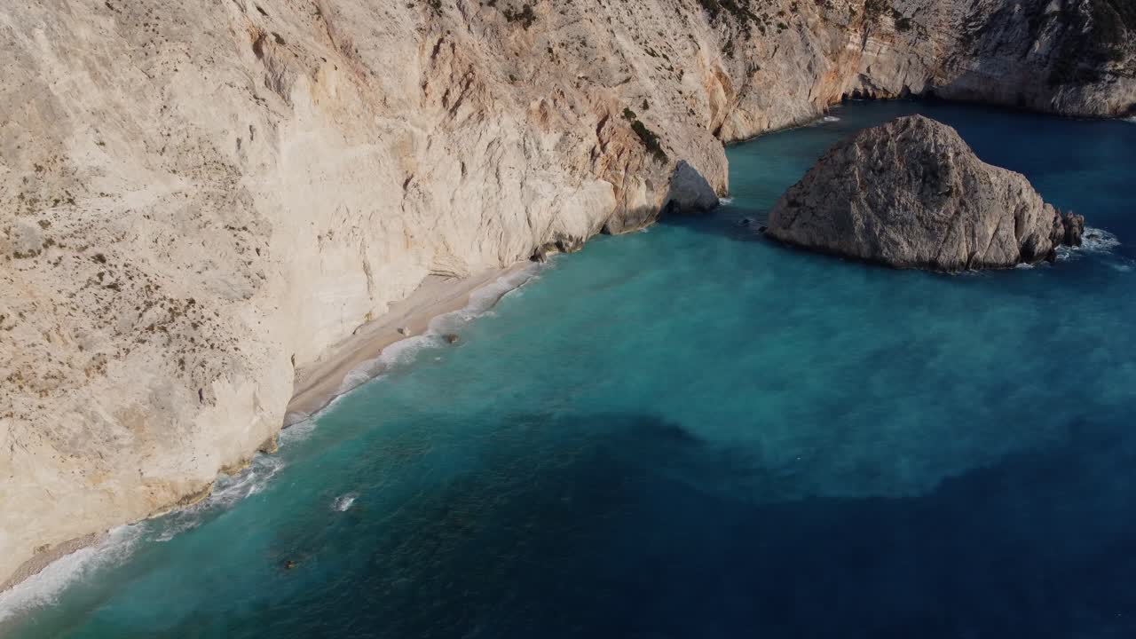 playa estrecha y aislada con agua azul celeste junto a un acantilado escarpado - mediterráneo