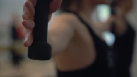 a close up of a lady hands in a gym excercising of her hands with small dumbbless in a gym