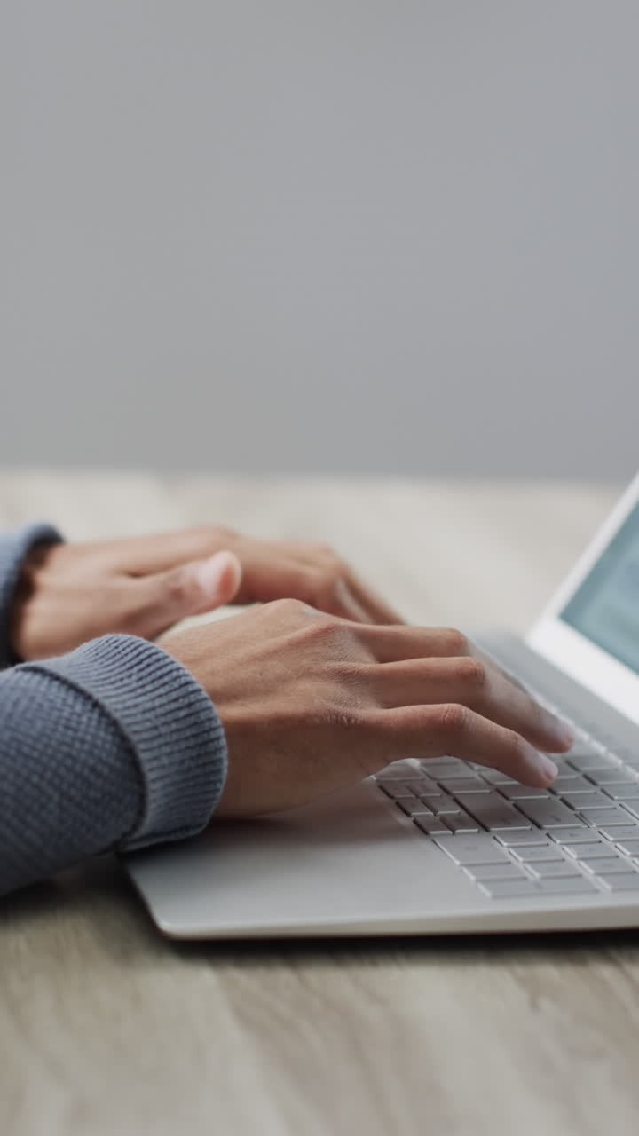 Vertical video of biracial businessman using laptop on grey background