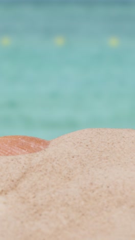 Vertical-Video-Summer-Holiday-Concept-With-Child's-Bucket-Spade-On-Sandy-Beach-Against-Sea-Background