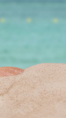 video concepto de vacaciones de verano vertical con la pala de cubo del niño en la playa de arena contra el fondo del mar