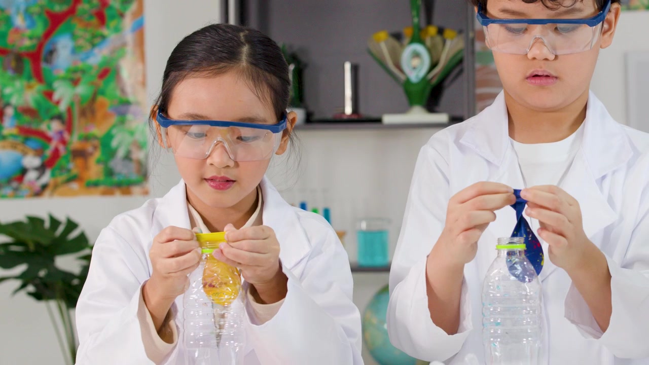 Dua siswa muda Asia mengenakan jas lab dan kacamata pelindung saat melakukan eksperimen sains STEM.