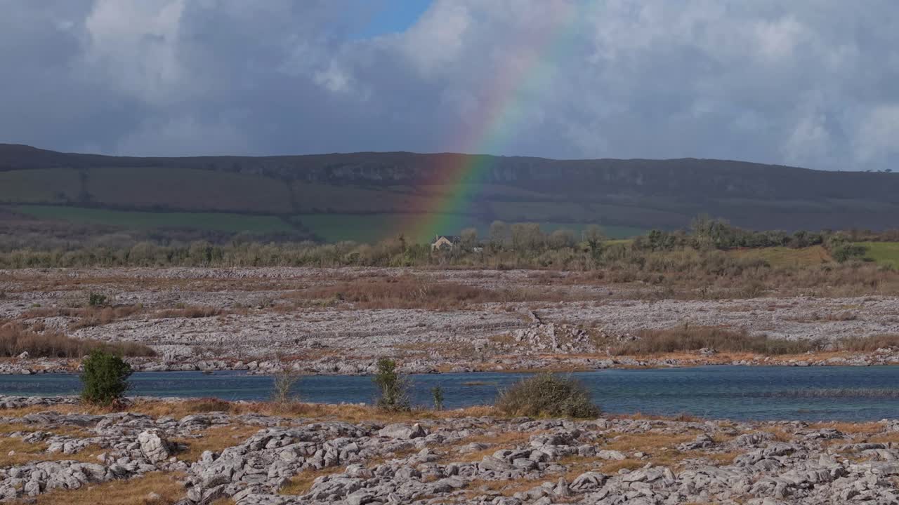 Vibrant rainbow over The Burren’s rocky karst landscape with a river in Ireland