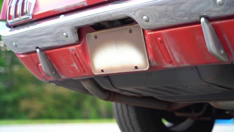 close-up view of a classic car's rear bumper and exhaust, highlighting details of vintage design and retro features in a natural outdoor setting