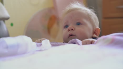 funny baby tries to climb up on soft bed with plaid in room