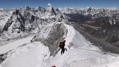 person walking on the summit of island peak in nepal with views of surrounding mountains.