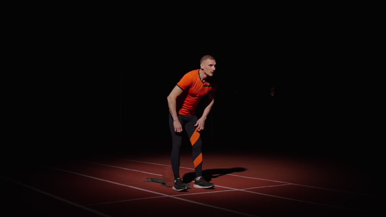 hombre en posición de salida en una pista por la noche