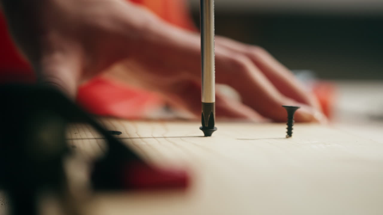 Primo piano di una mano che avvita una vite in una tavola di legno