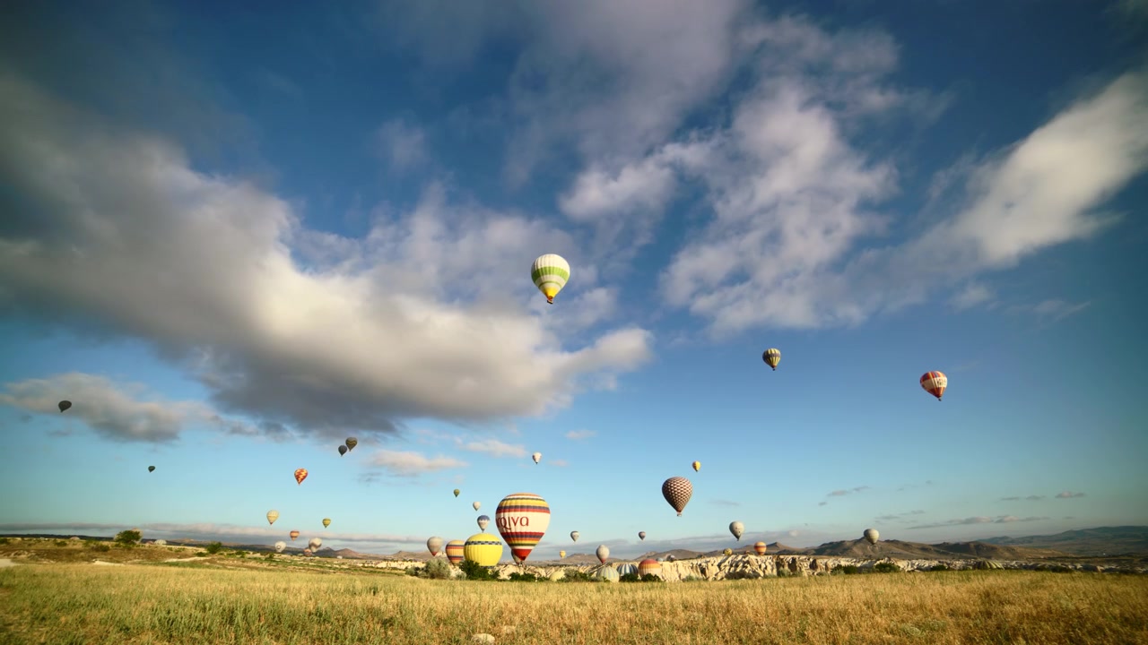 Gün doğumunda Kapadokya manzarası üzerinde uçan birçok sıcak hava balonu