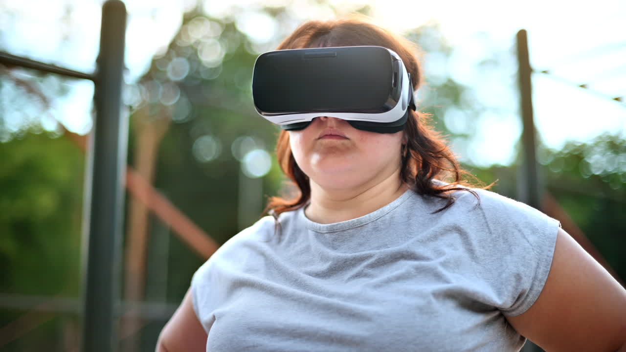 Donna in sovrappeso che indossa un visore per la realtà virtuale su un campo sportivo in un parco