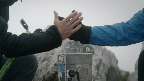 un apretón de manos de felicitación en la cima de un stol de montaña dando cada uno a otros dos excursionistas