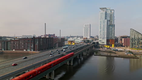 Metro-subway-approaching-Redi-towers-skyscrapers-in-Kalasatama,-Helsinki-along-bridge-over-water