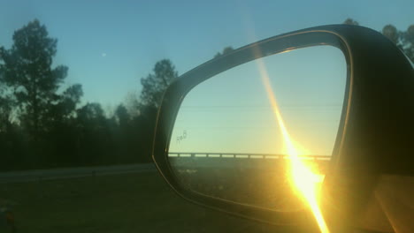 sunset in the rear view mirror of a rav4 car cruising on a clean highway