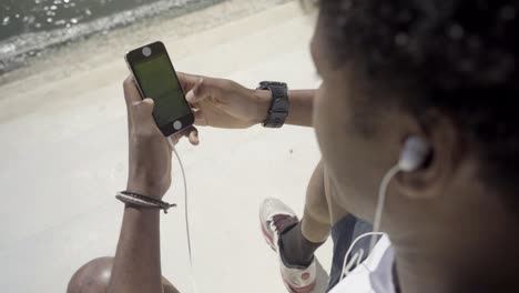 African-American-young-man-with-digital-devices-on-embankment.