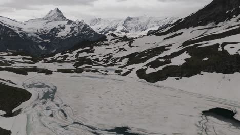 Aerial-establishing-view-of-ice-and-snow-covered-Bachalpsee-Lake-Switzerland,-drone-descends