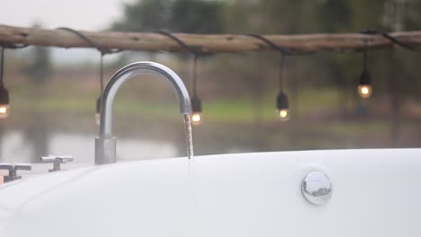 water flowing from faucet into a bathtub outdoors