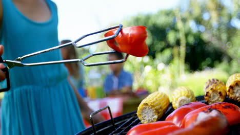 girl flipping bell pepper on barbecue