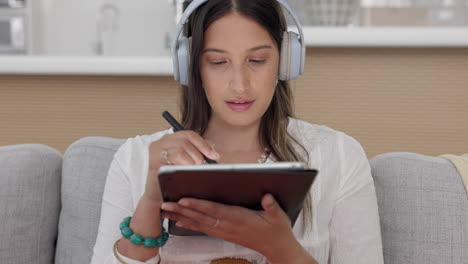 Woman-on-sofa-with-tablet,-headphones-and-drawing