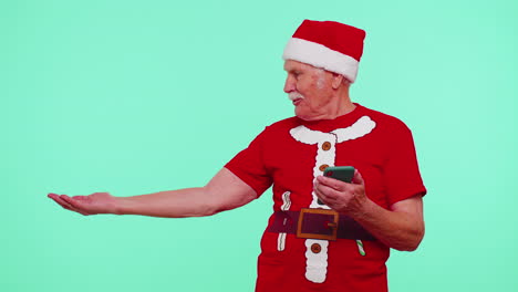 Grandfather-Santa-Christmas-t-shirt-with-mobile-phone-showing-pointing-empty-place,-advertising-area