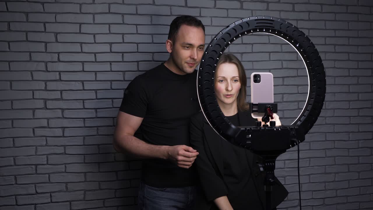 video de una pareja de bloggers con una lámpara led de anillo en el fondo de la pared de ladrillo