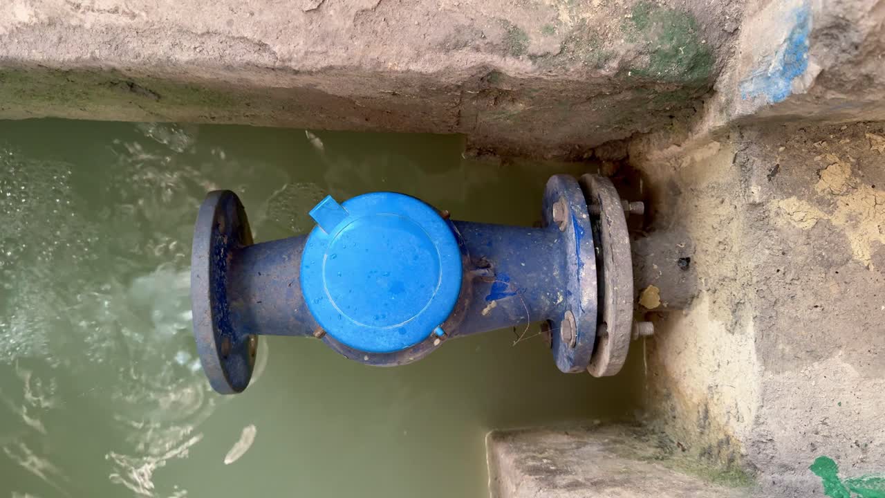 Heavy water stream coming from blue industrial pipeline into wastewater treatment plant