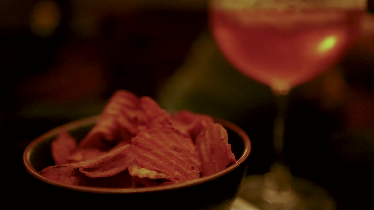 Patatine e cocktail su un tavolo in penombra