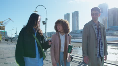 young business people walking on urban riverbank and having talk