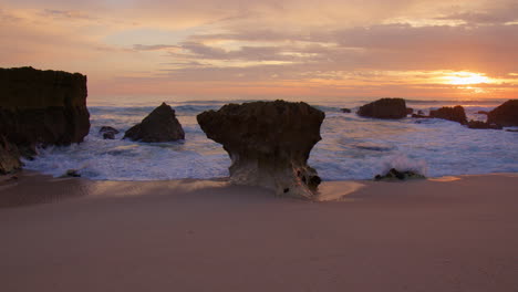 rugged rock formations on sandy beach in algarve, portugal at sunset - wide