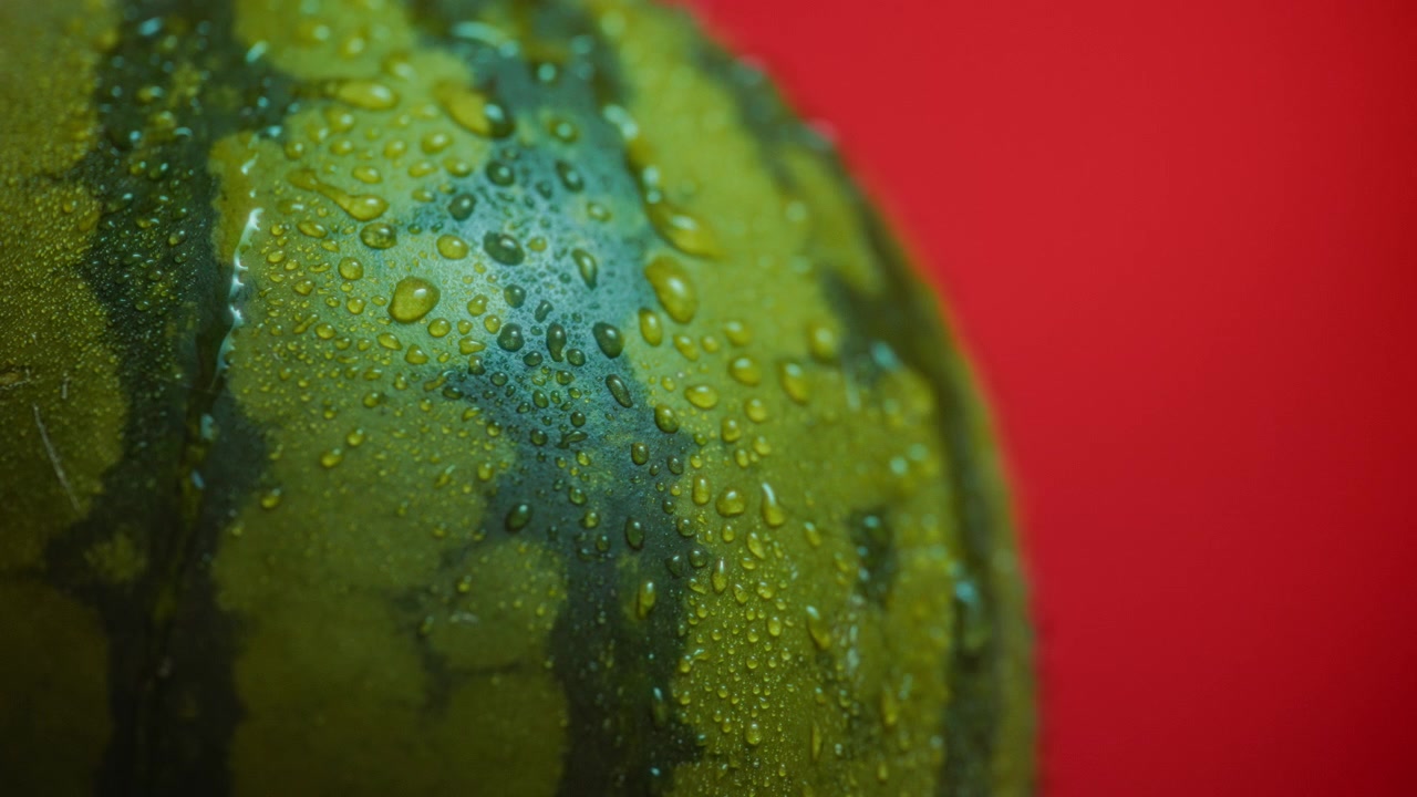 Acqua che scorre sull'anguria su sfondo rosso.