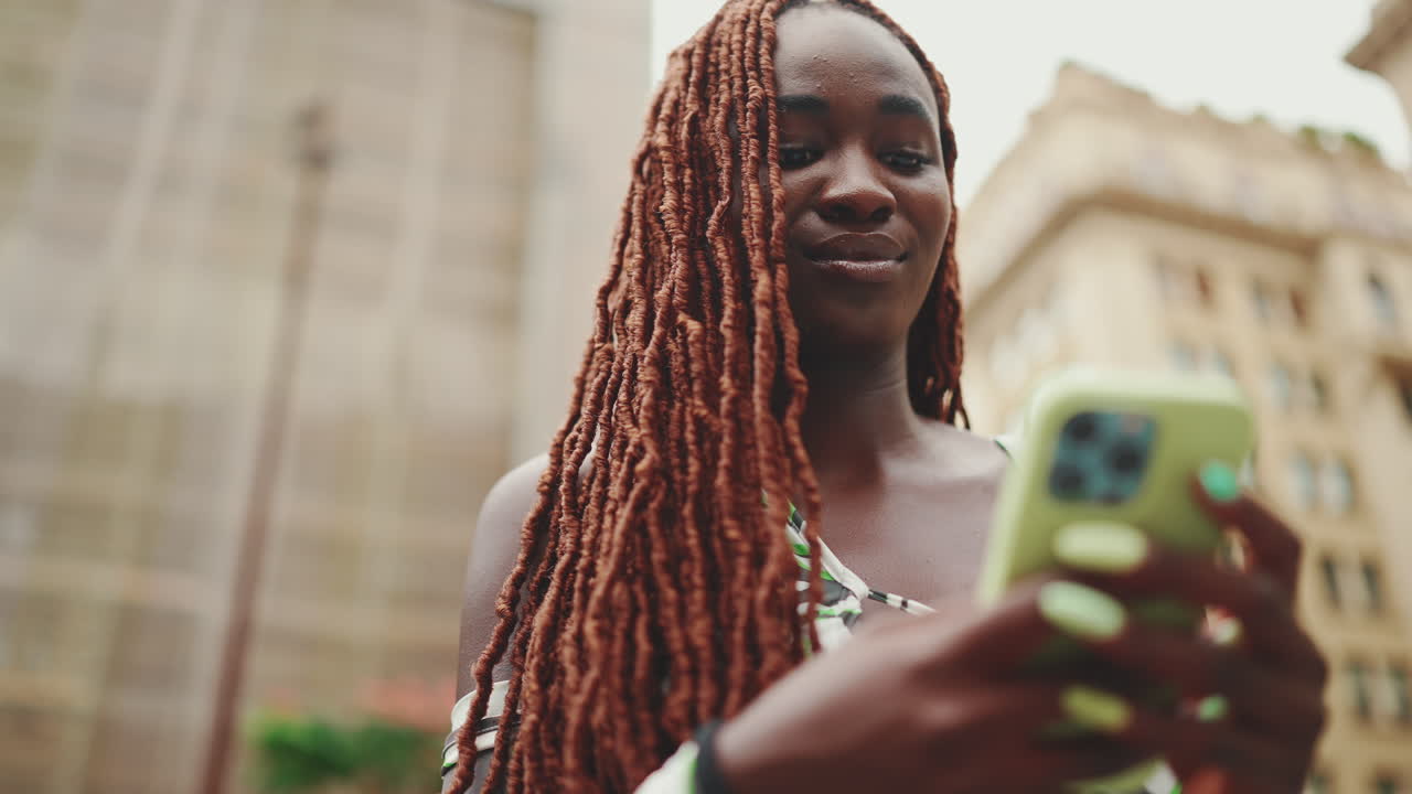 Donna con dreadlock che usa lo smartphone in città