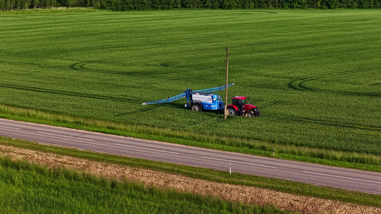 Tractor spraying pesticides standing in the field. Aerial