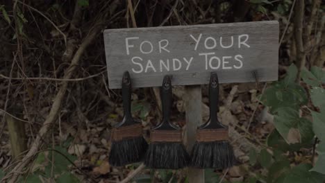 Three-Black-Brush-Hanging-On-A-Board-With-For-Your-Sandy-Toes-Sign