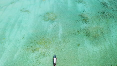 motor boat sailing against ocean tide in shallow turquoise waters