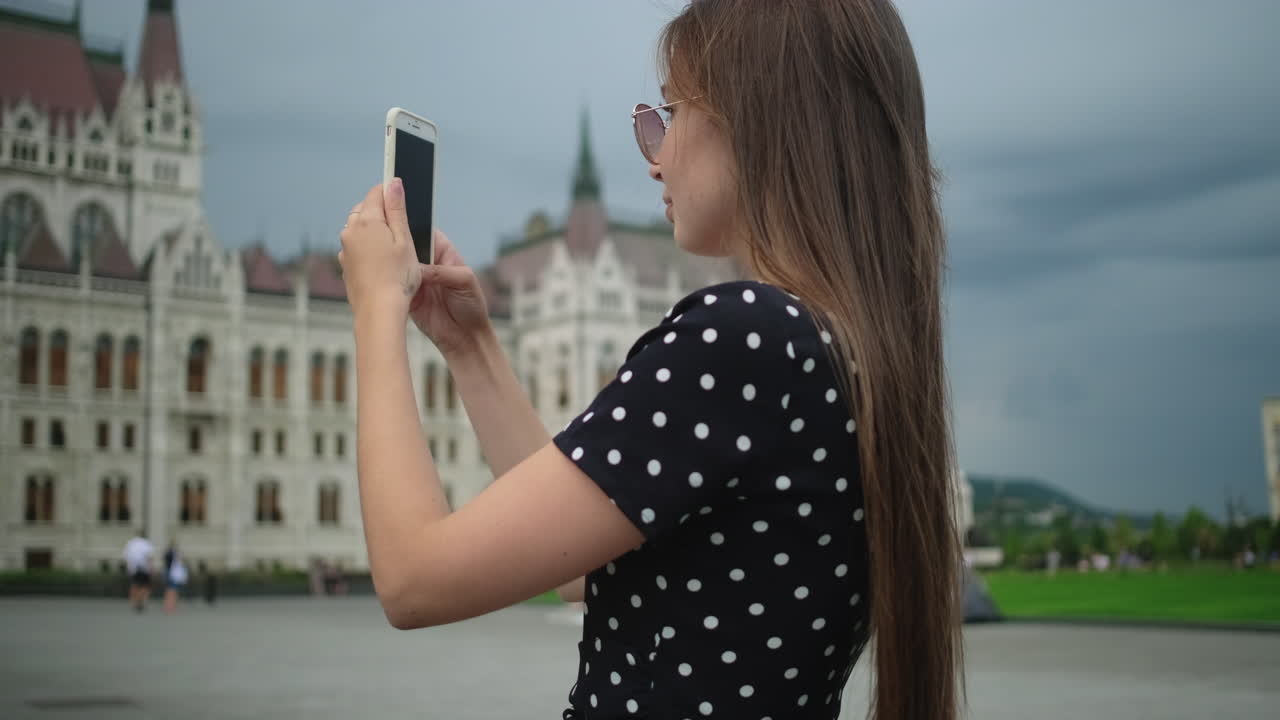 mujer tomando una foto del edificio del parlamento húngaro